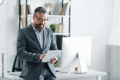 Fotomural handsome businessman in formal wear using digital tablet in office