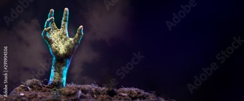Fotografía Photo of zombie hand sticking out of grave, black background.
