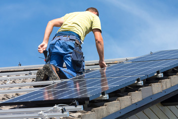 Installing solar photovoltaic panel system. Solar panel technician installing solar panels on roof. Alternative energy ecological concept.