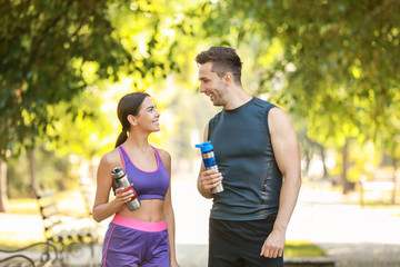 Sticker - Sporty young couple with bottles of water in park