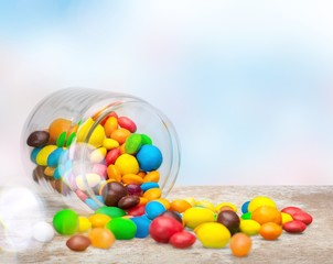 Wall Mural - Colorful candies sweets falling out of a glass jar, composition isolated over the white background