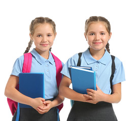 Wall Mural - Portrait of twin girls with school bags and books on white background