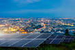Solar panel with city night architecture electric energy light background,clean Alternative power energy concept.