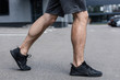 © LIGHTFIELD STUDIOS - partial view of sportsman in black sneakers walking on street