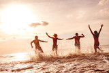 Fototapeta  - Happy friends having fun at sunset sea beach