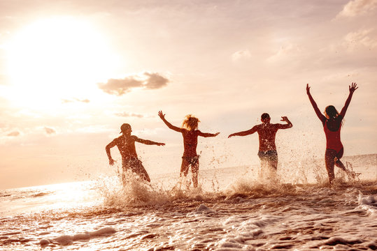 Happy friends having fun at sunset sea beach