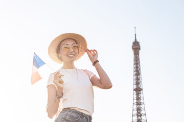 Wall Mural - Happy asian woman traveler posing at Mars Field at the background of majestic Eiffel tower. Tourism and lifestyle in France and Paris. Vacation in Europe.