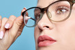 © Serg Zastavkin - Close-up portrait of attractive young woman in glasses on blue background