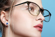 © Serg Zastavkin - Close-up portrait of attractive young woman in glasses on blue background