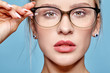 © Serg Zastavkin - Portrait of attractive young woman in glasses on blue background