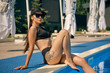 © nazarovsergey - Portrait of a female having rest and posing in a swimming pool. Dressed in a black swimsuit, sunvisor cap and sunglasses.