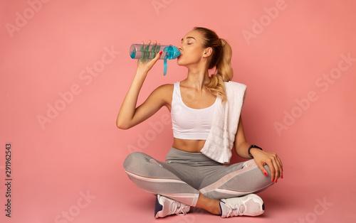 Fotomural Fitness Woman Drinking Water Sitting On Floor In Studio