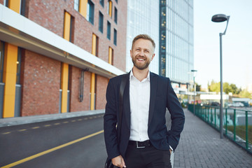 A smiling businessman is standing on the street.