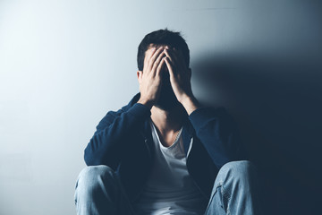 Wall Mural - sad man sitting on ground on dark background