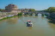 Tourist Boat and the Sant'Angelo Castle on the banks of the river Tiber in Rome, Italy