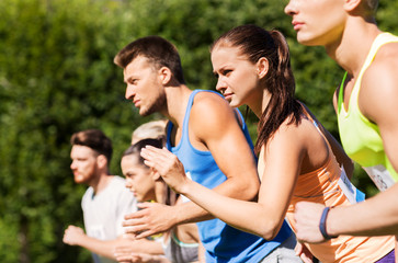 Poster - fitness, sport, race and healthy lifestyle concept - group of people or sportsmen with badge numbers on start of running marathon at summer park