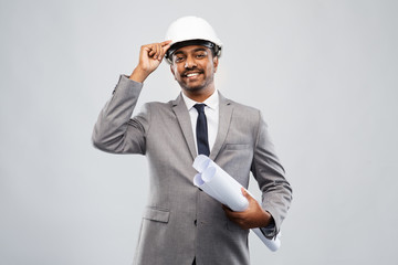 Sticker - architecture, construction business and people concept - smiling indian male architect in helmet with blueprints over grey background