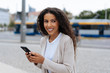 © contrastwerkstatt - Young woman holding her mobile in an urban street