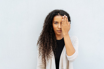 Young African woman covering an eye with a hand