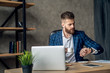 © Roman - Handsome male lawyer looking at wristwatch while drinking coffe sitting at digital computer. Bearded economist in formal wear checking time on smartwatch to finish work on time