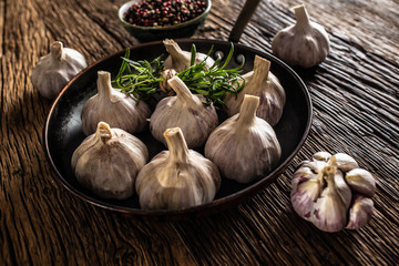 Wall Mural - Garlic cloves and bulb in pan with fresh rosemary on old wooden table