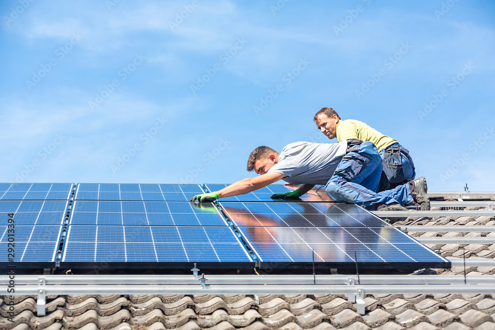Installing solar photovoltaic panel system. Solar panel technician installing solar panels on roof. Alternative energy ecological concept. - obrazy, fototapety, plakaty 