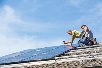 Wall Mural - Installing solar photovoltaic panel system. Solar panel technician installing solar panels on roof. Alternative energy ecological concept.