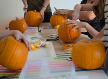 Group Of People Carving Pumpkin To Make Jack-o-lantern. Creating Traditional Decoration For Halloween And Thanksgiving. Cutted Orange Pumpkin Lay On Table.