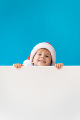 Happy child holding white Christmas banner blank against blue background