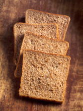 Four Slices Of Wholemeal Bread Against Wood Background