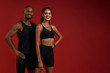 © Friends Stock - Healthy and happy. Young and cheerful african fitness couple in sportswear looking at camera with smile while standing against red background
