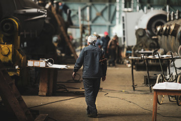 Woman welder in a dirty and old but still functioning metal works, old fashioned, factory