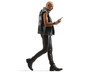 Bald punk in leather clothing waling and looking at his mobile phone