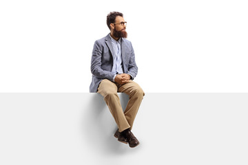 bearded man sitting on a white banner and looking to the side