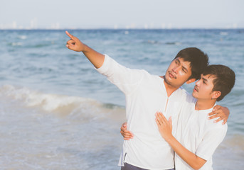 Homosexual portrait young asian couple standing pointing something together on beach in summer, asia gay going sea for leisure with romantic and happy in vacation at sea, LGBT with legal concept.