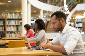 Wall Mural - mix raced trainees working on computer in public library. serious people sitting at desks and using 