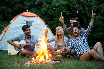 Wall Mural - Happy friends enjoying music near campfire at night