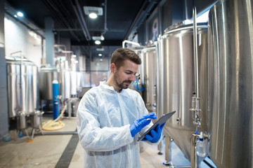 Technologist expert using tablet computer in food factory production line. Factory worker controlling production.