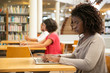 © Mangostar - Focused female customer using public wi-fi hotspot in library. Young African American woman sitting at desk and using laptop. Wireless internet connection concept