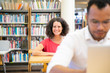 © Mangostar - Joyful female adult student enjoying training course in classroom. Happy middle aged Caucasian woman in casual sitting at desk and smiling at camera. Bookshelves in background. Library concept