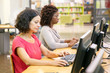© Mangostar - Diverse female trainees working in computer class. Women in casual sitting at table, using desktops, typing, looking at monitor. Training course concept