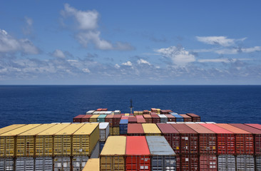 Large cargo container ship loaded with colorful containers sailing through a blue ocean.  