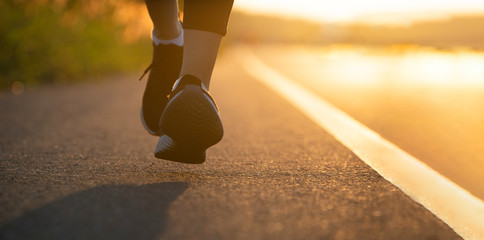 Wall Mural - Runner feet running on road closeup on shoe. Woman fitness sunrise jog workout wellness concept. Young fitness woman runner athlete running at road