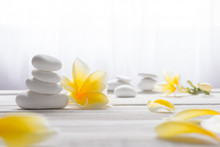 Stacked White Stones On White Background With Yellow Frangapani Flower - Lifestyle And Alternative Health Concept Image With Copy Space For Text.