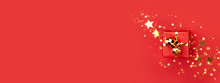 Banner With Red Gift Box With Golden Bow On Red Background Decorated Golden Stars Confetti. Top View, Minimal Styled Christmas And Holiday Concept.