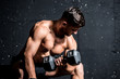 © Srdjan - Young strong muscular sweaty fit man biceps muscle cross workout training with heavy dumbbell weight in the gym dark image with shadows real people