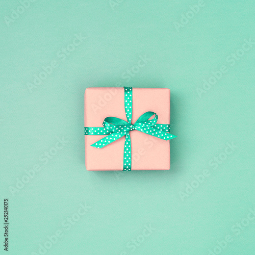 One gift box with mint ribbon in polka dots on mint background. Top view, pla...