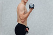 Beautiful man lifting dumbbell in home. He training biceps