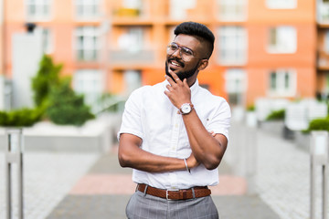 Wall Mural - Happy bearded Indian modern young businessman smiling in the streets outdoors