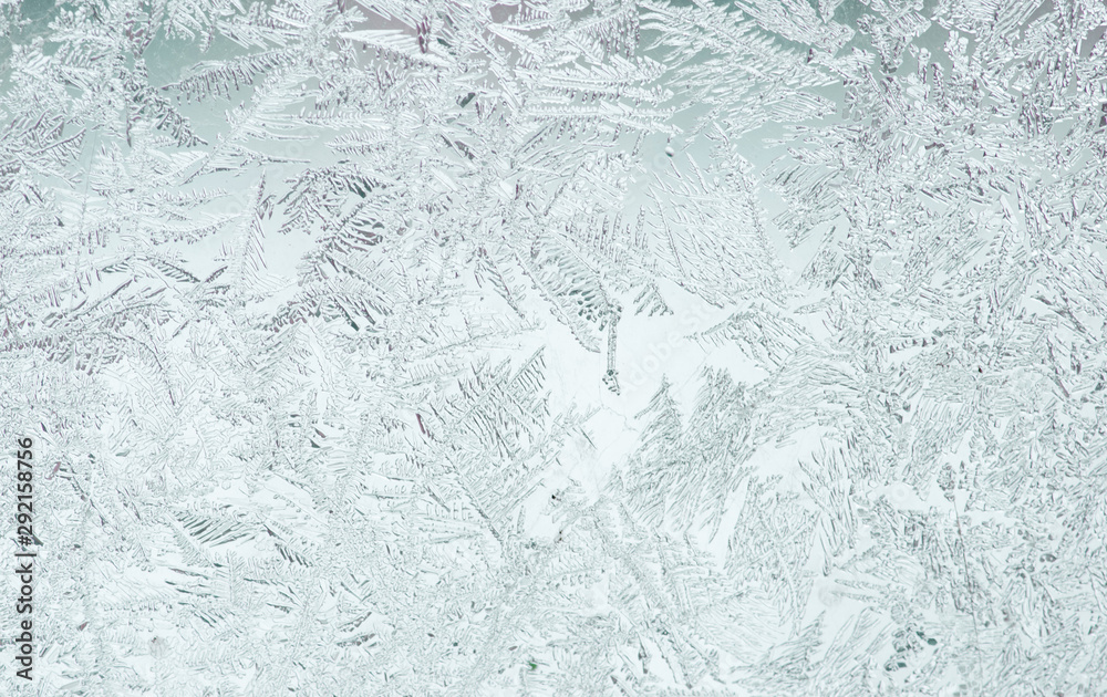 beautiful festive frosty pattern with white snowflakes on a blue background on glass - obrazy, fototapety, plakaty 